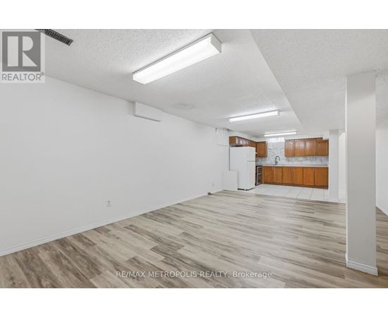 A spacious room with wooden flooring and white walls.
