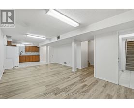 A spacious room with wooden flooring and white walls.