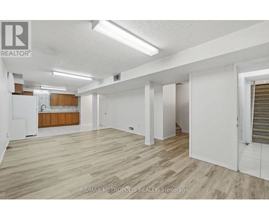 A spacious room with wooden flooring and white walls.