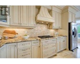 A kitchen with white cabinets and a marble countertop.