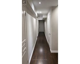 A long hallway with white walls and wood floors.