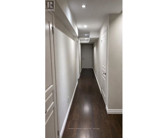 A long hallway with white walls and wood floors.