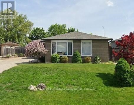 A house with a green lawn and a red tree in the front yard.