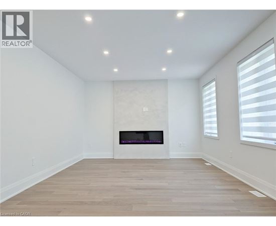 A spacious room with a fireplace and wooden flooring.