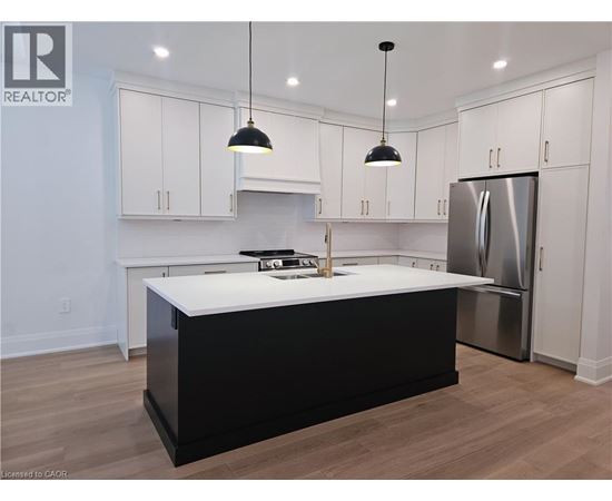 A kitchen with white cabinets and a black island.