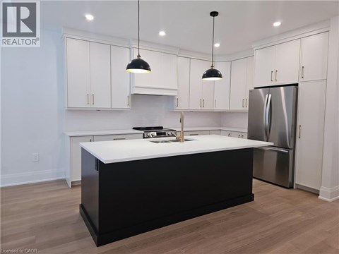 A kitchen with white cabinets and a black island.