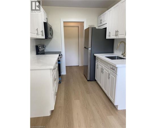 A kitchen with white cabinets and a black fridge.