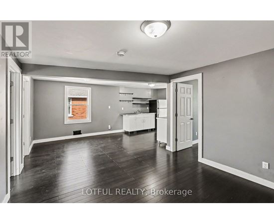 A spacious room with a kitchen area in the background.