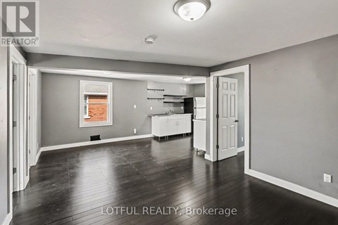 A spacious room with a kitchen area in the background.