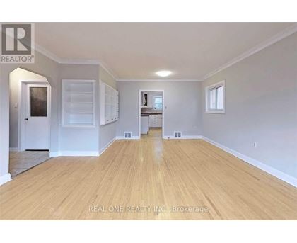 A spacious room with wooden flooring and white walls.