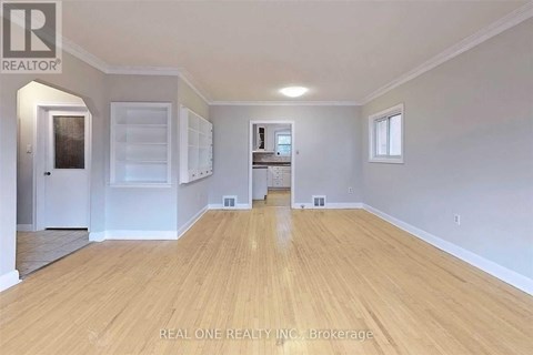 A spacious room with wooden flooring and white walls.