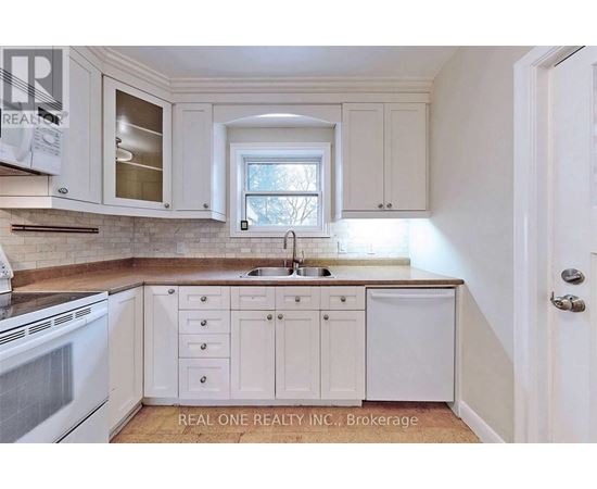 A kitchen with white cabinets and a window above the sink.