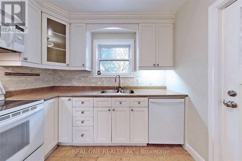 A kitchen with white cabinets and a window above the sink.