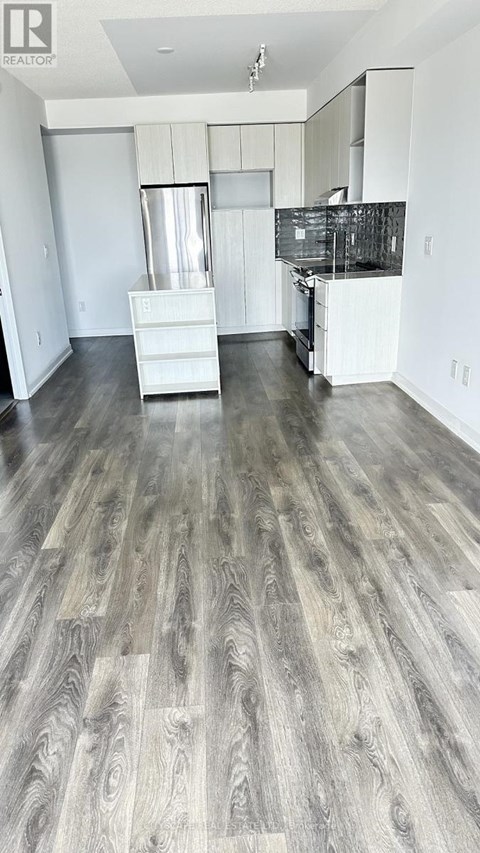 A spacious kitchen with white cabinets and a wooden floor.