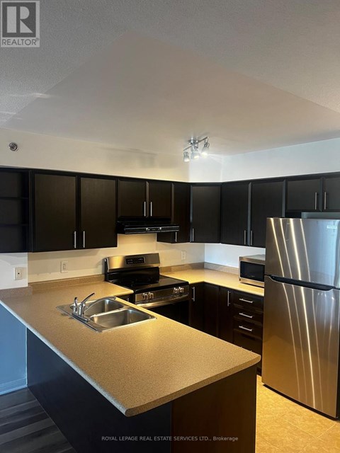 A kitchen with black cabinets and a stainless steel refrigerator.