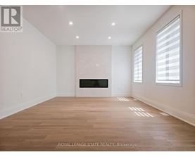 A spacious room with wooden flooring and a fireplace.
