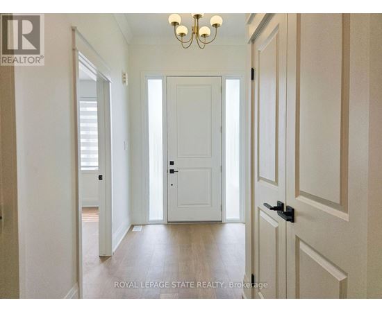 A hallway with a white door and a chandelier.