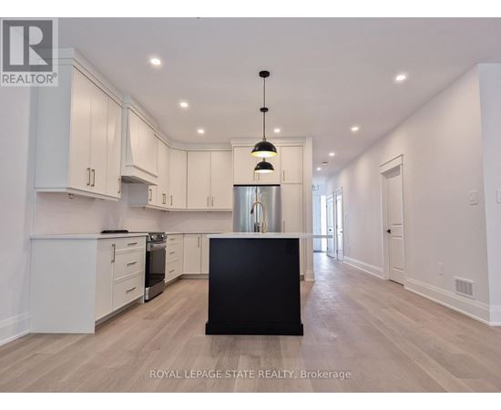 A spacious kitchen with white cabinets and a black island.