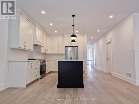 A spacious kitchen with white cabinets and a black island.