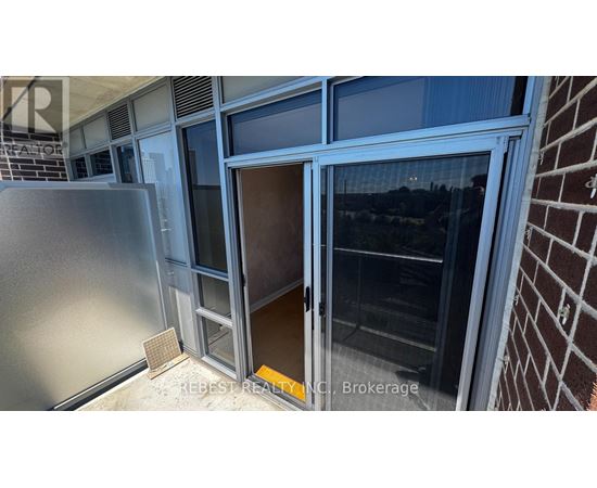 A view from the balcony of a building with a glass door and a brick wall.