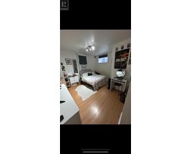 A bedroom with a bed, desk, and a poster on the wall.