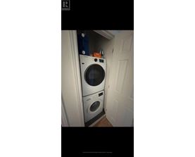 A washing machine is placed in a small space between a door and a wall.