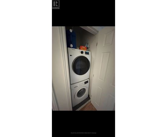 A washing machine is placed in a small space between a door and a wall.