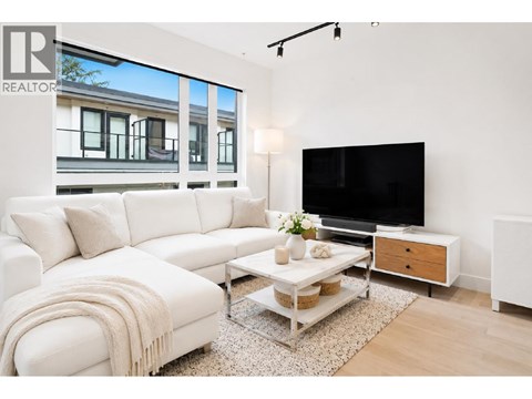 A living room with a white couch and a flat screen TV.