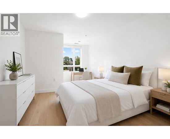 A bedroom with a large bed, a nightstand, and a dresser with a mirror.