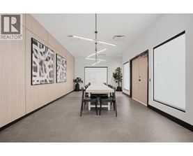 A modern office space with a dining table and chairs in the middle.