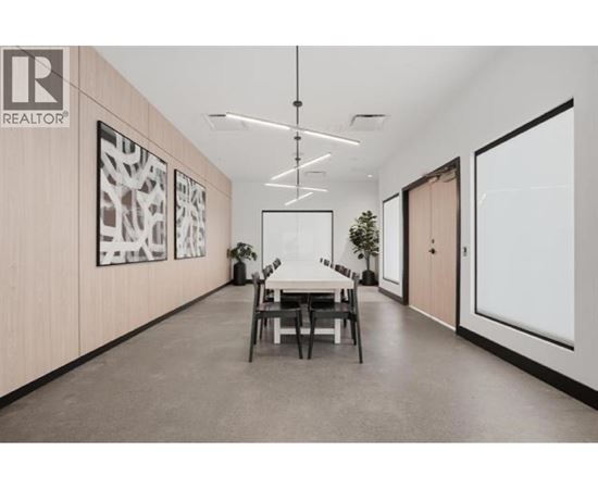 A modern office space with a dining table and chairs in the middle.