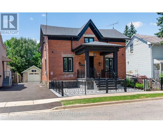 A red brick house with a black iron fence in front.