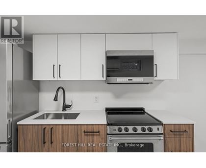 A kitchen with a sink, stove and cabinets.