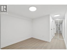 A white room with a wooden floor and a doorway leading to another room.