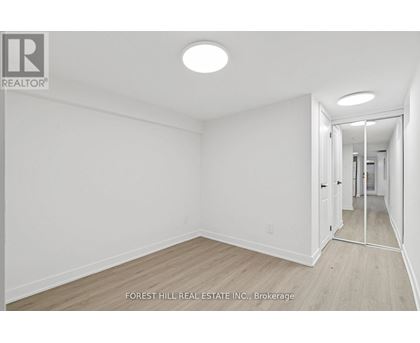 A white room with a wooden floor and a doorway leading to another room.