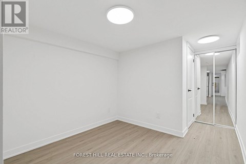 A white room with a wooden floor and a doorway leading to another room.