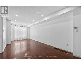 A spacious room with wooden flooring and white walls.