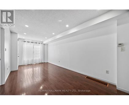 A spacious room with wooden flooring and white walls.