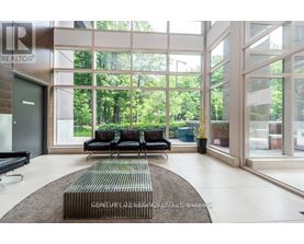 A living room with a couch and a rug in front of a glass wall.