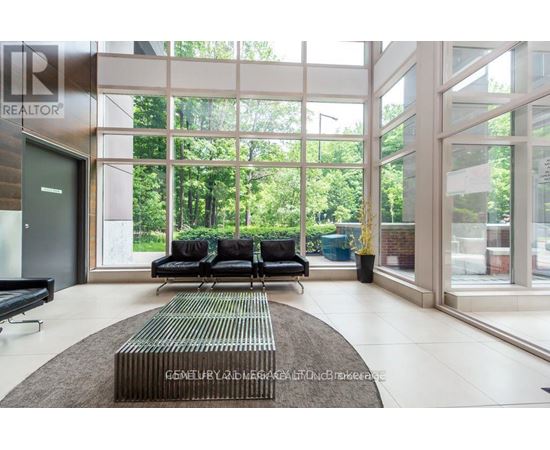 A living room with a couch and a rug in front of a glass wall.