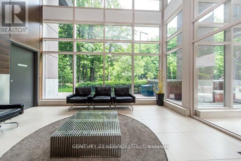 A living room with a couch and a rug in front of a glass wall.