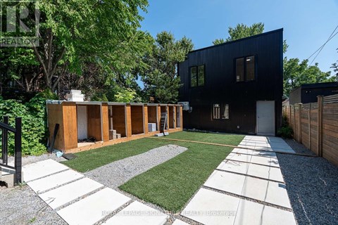 A modern black house with a gravel and grass yard.