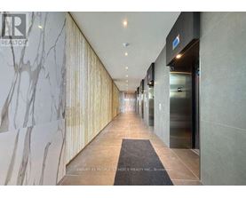 A hallway with a marble wall on the left and a glass door on the right.