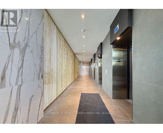 A hallway with a marble wall on the left and a glass door on the right.
