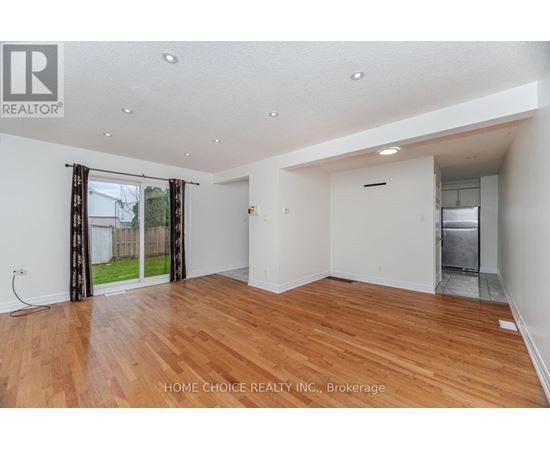 A spacious room with wooden flooring and white walls.