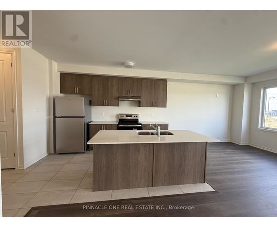 A kitchen with a refrigerator, sink, and stove top oven.