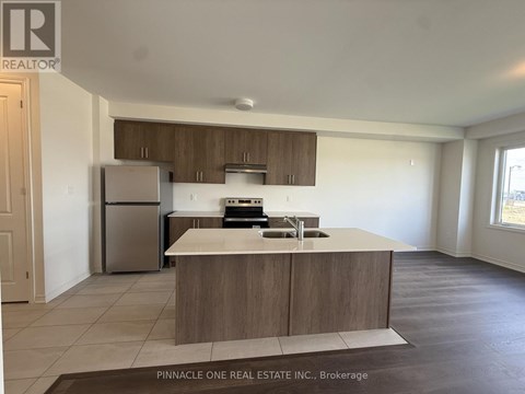 A kitchen with a refrigerator, sink, and stove top oven.