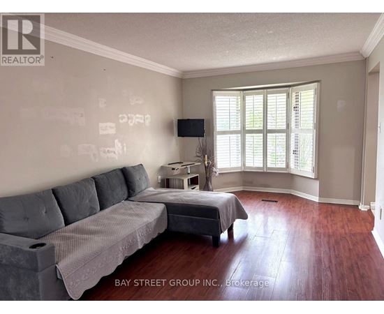 A living room with a grey couch and a bed with a grey bedspread.