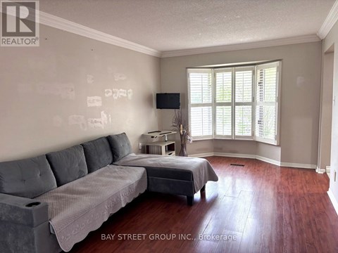A living room with a grey couch and a bed with a grey bedspread.