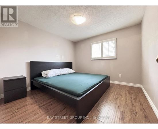 A bedroom with a bed, nightstand, and window.